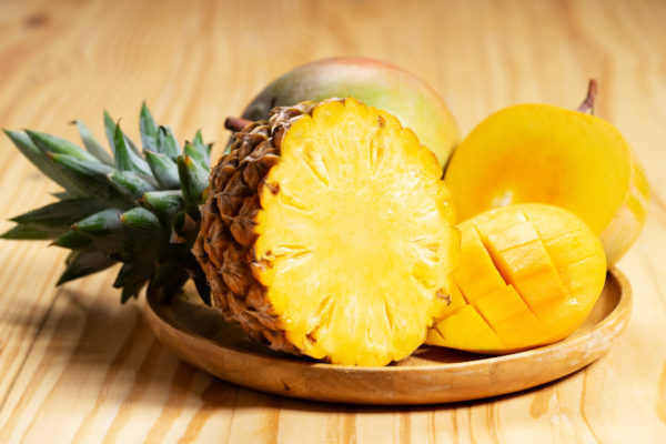 A pineapple and other fruits on a plate.